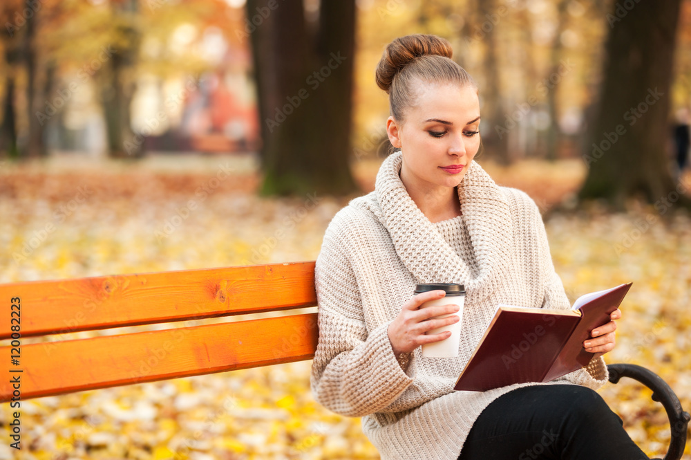 Obraz premium Pretty caucasian female drinking coffee and reading