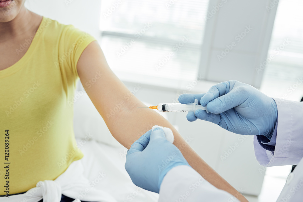 Fototapeta premium Young woman receiving medication injection in hospital