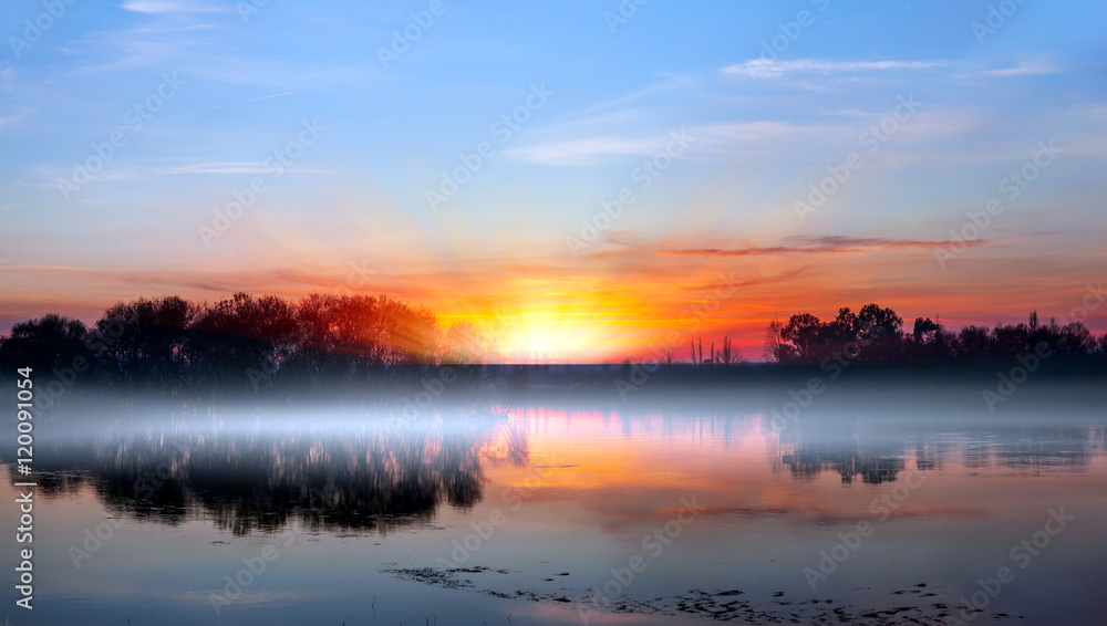 birds silhouettes flying above the lake against sunset