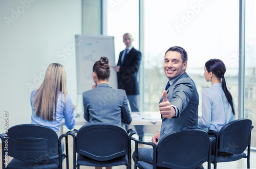 businessman with team showing thumbs up in office