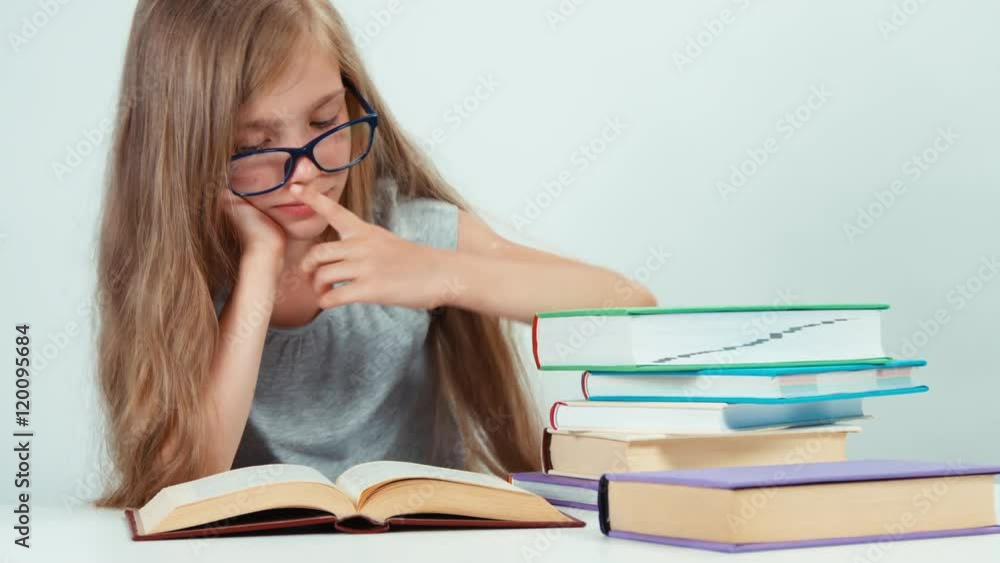Close up portrait student girl with long blond hair 7-8 years in glasses reading book and adjusts glasses Close up portrait student girl with long blond hair 7-8 years in glasses reading book and adjusts glasses
