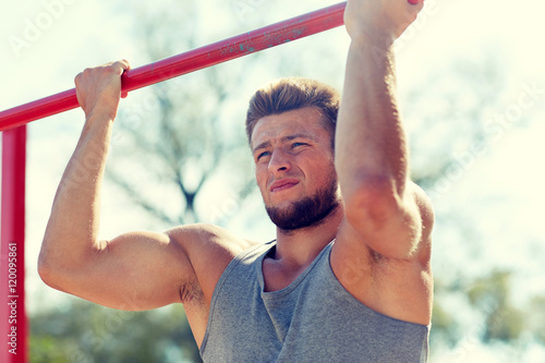 young man exercising on horizontal bar outdoors