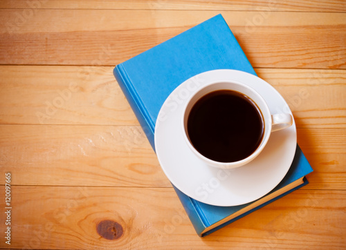 Coffee cup and book on wooden background. Top view