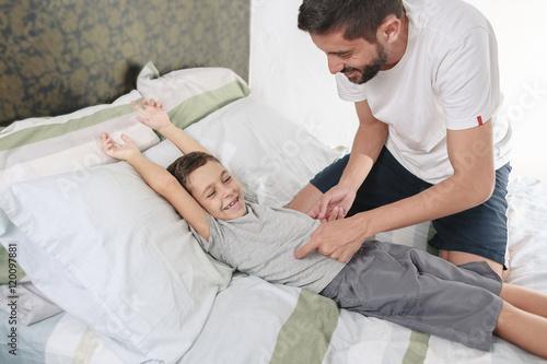 Foto Father tickling his son on the bed