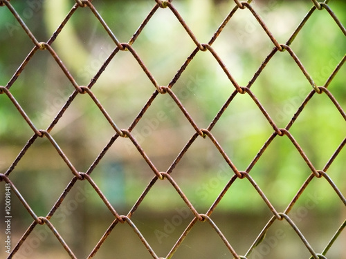 Rust steel metal net for security fence with blur nature green in background.
