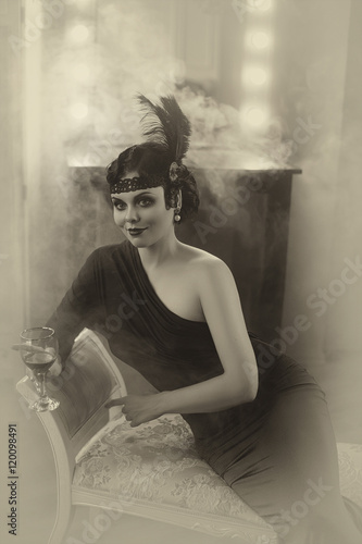 Beautiful Flapper girl with wineglass. Old photo in a retro style. Smoky eyes, hairstyle cold wave. Creative colors