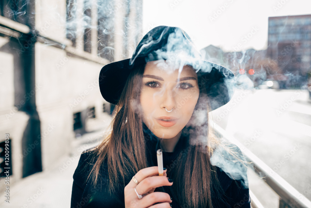 Fototapeta premium young beautiful woman smoking in the city backlight winter