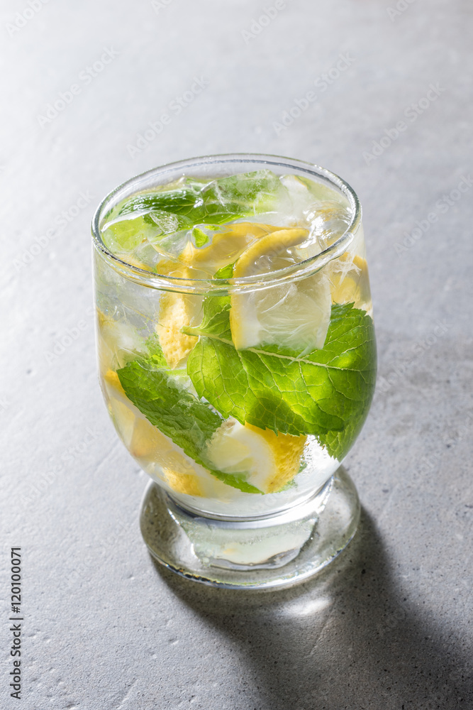 Fototapeta premium Refreshing lemonade with mint leaves and ice on gray stone table