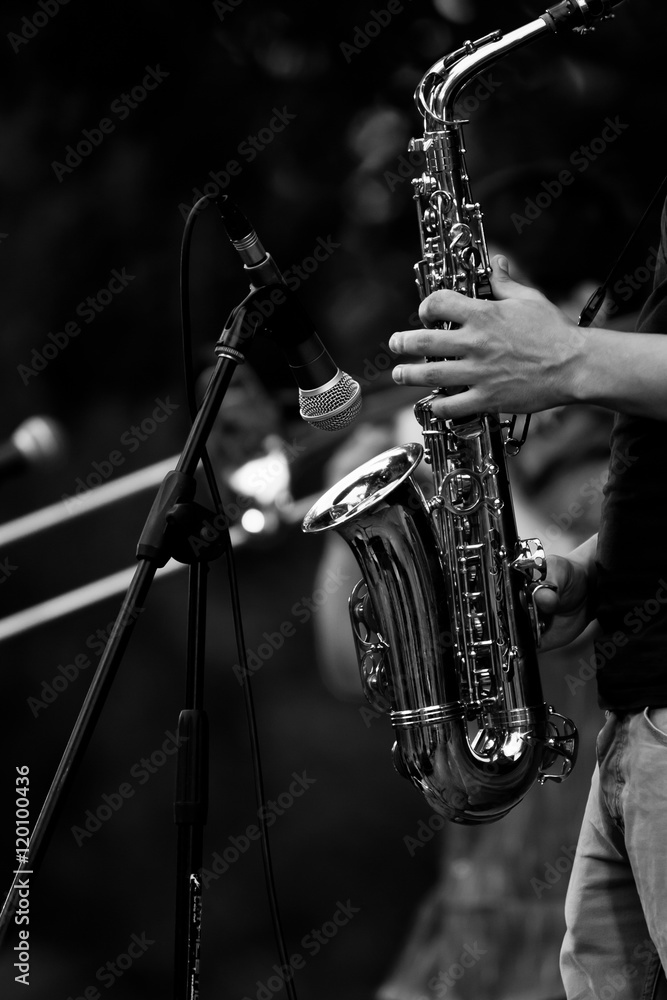 Fototapeta premium Saxophone in the hands of a musician at a concert in black and white