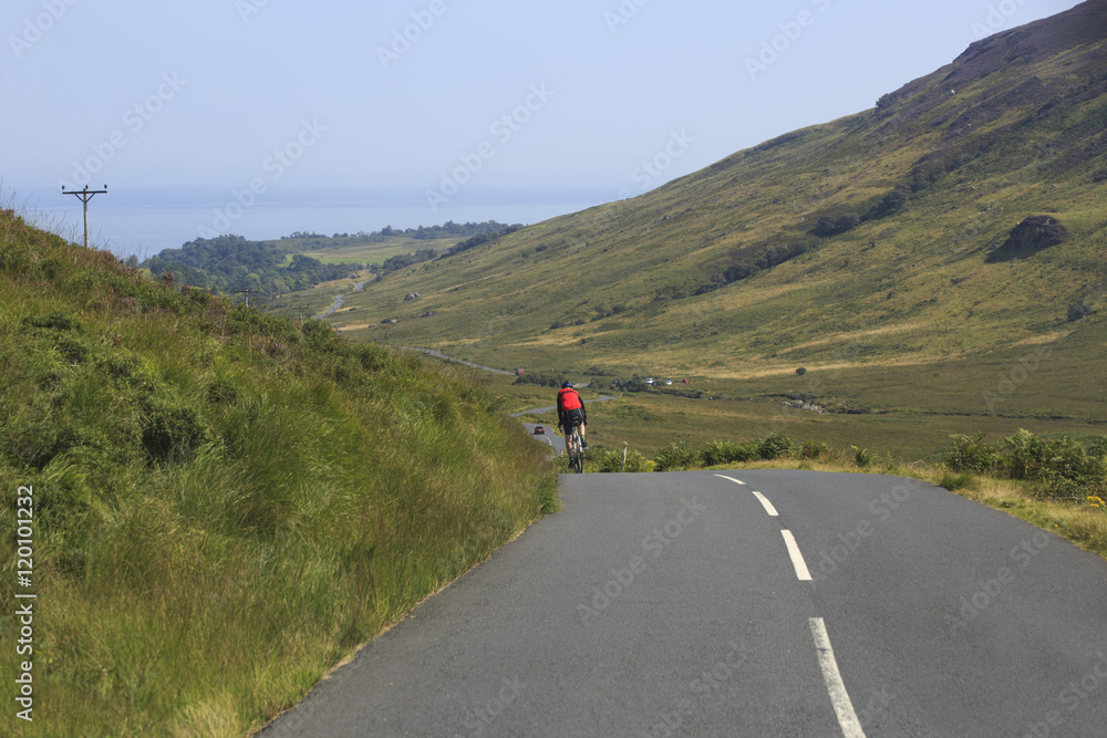 Fototapeta premium Cyclist travelling on a winding road