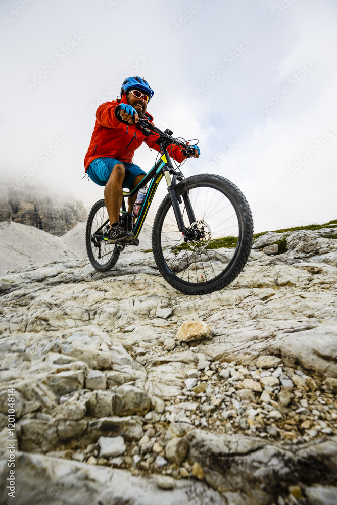 Mountain Bike cyclist riding single track on rocks healthy lifestyle active vacation in italian Alps