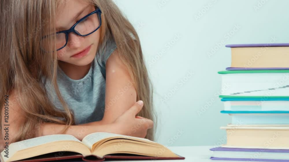 Extreme close up portrait cute student girl with long blond hair 7-8 years in glasses reading book Extreme close up portrait cute student girl with long blond hair 7-8 years in glasses reading book