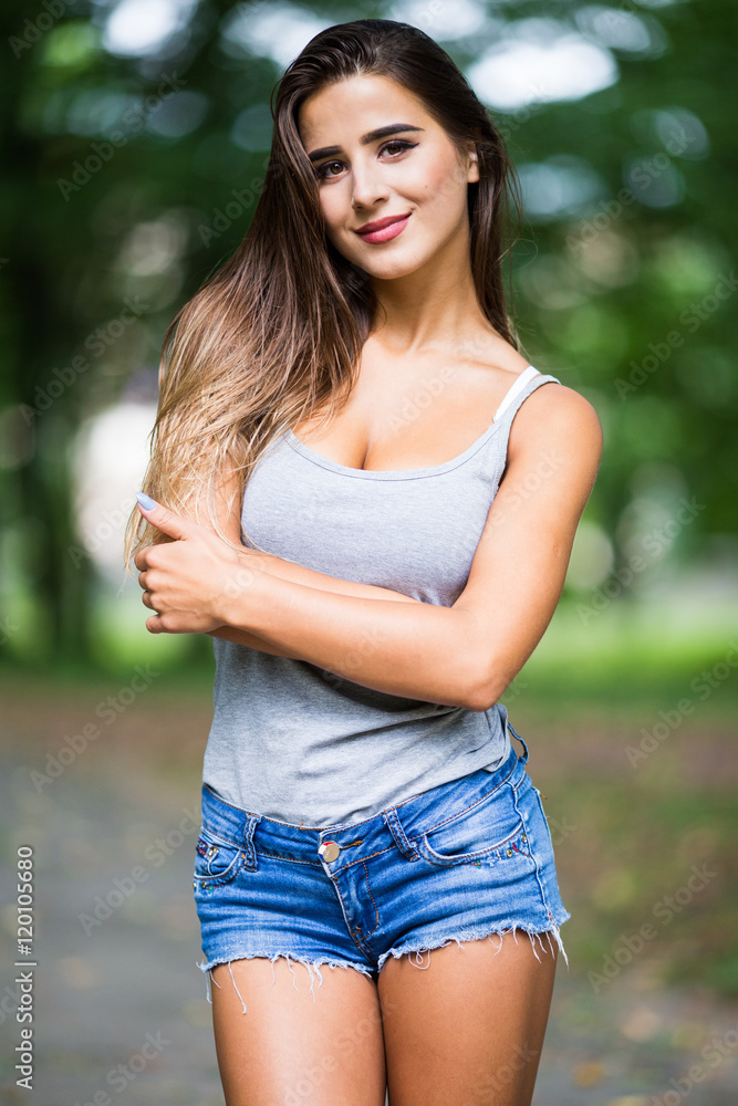 Beautiful young woman walking in summer park