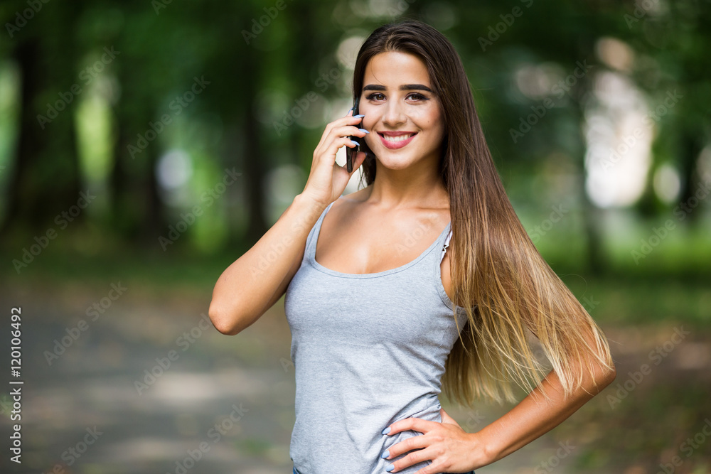 Beautiful woman talking on cell phone in the park Beautiful woman talking on cell phone in the park