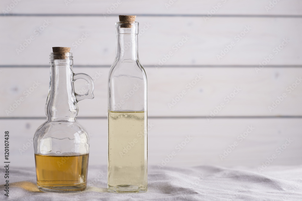 Transparent bottles with oil and vinegar on white wooden background. Transparent bottles with oil and vinegar on white wooden background.