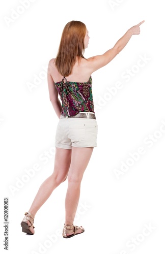 Back view of pointing woman. beautiful brunette girl in shorts. Rear view people collection. backside view of person. Isolated over white background.