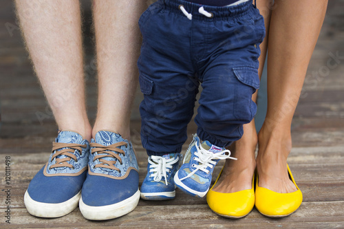 Семья: ноги маленького мальчика в джинсовых кроссовках, ноги папы в джинсовых кедах и ноги мамы в желтых туфлях-балетках 