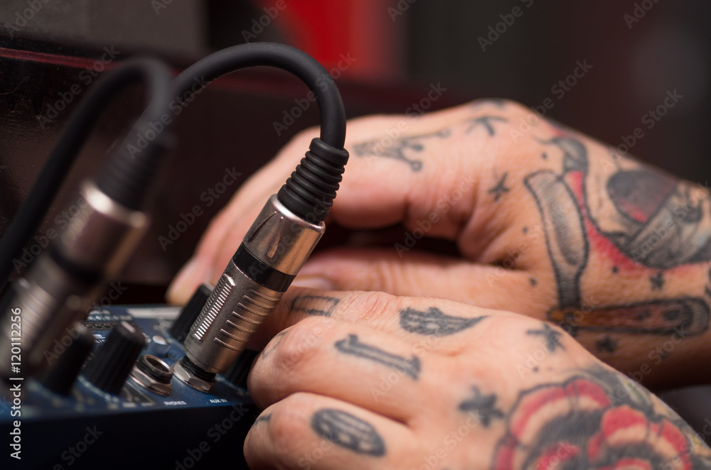 Closeup of hands covered with tattoos working on cable connection hardware  audio box, studio equipment concept Photos | Adobe Stock