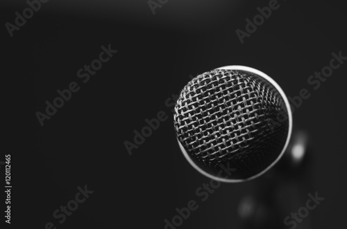 Closeup black vocal microphone mounted on mic stand, blurry red dark bcakground © Fotos 593