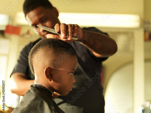 Bild auf Leinwand little boy in barbershop getting head shaved