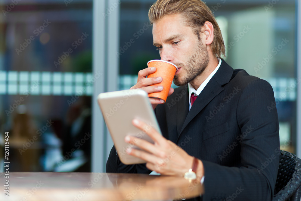 Businessman using his tablet computer while drinking coffee Businessman using his tablet computer while drinking coffee
