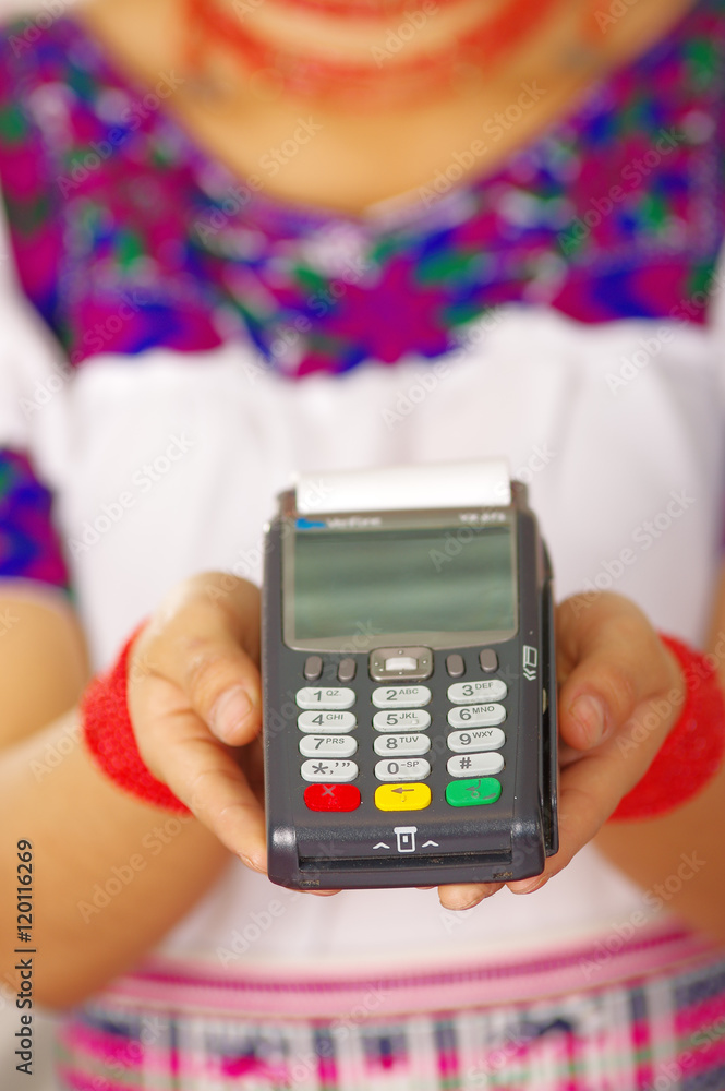 Closeup credit card terminal, woman wearing traditional andean indigenous clothing holding device in front of camera Closeup credit card terminal, woman wearing traditional andean indigenous clothing holding device in front of camera