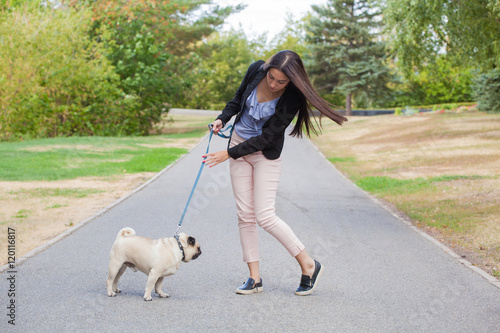 Sport girl and pug on a leash walk in the park