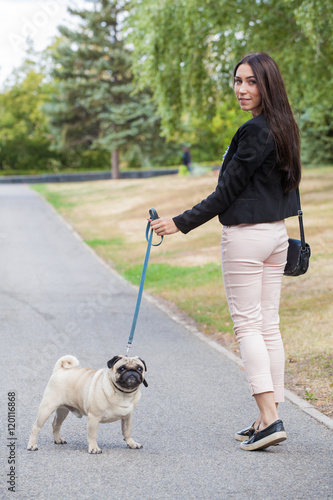 Sport girl and pug on a leash walk in the park