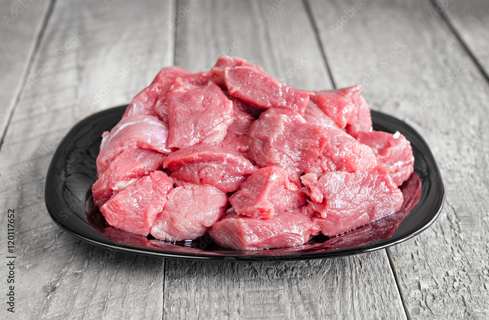 Raw veal meat on a plate and gray wooden background Raw veal meat on a plate and gray wooden background