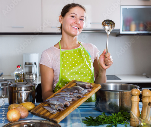 Woman cooking stew with sardines photo