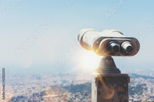 Touristic telescope look at the city view of Barcelona, close up old metal binoculars background overlooking the mountain, hipster coin operated in panorama observation nature blue sky, mockup flare