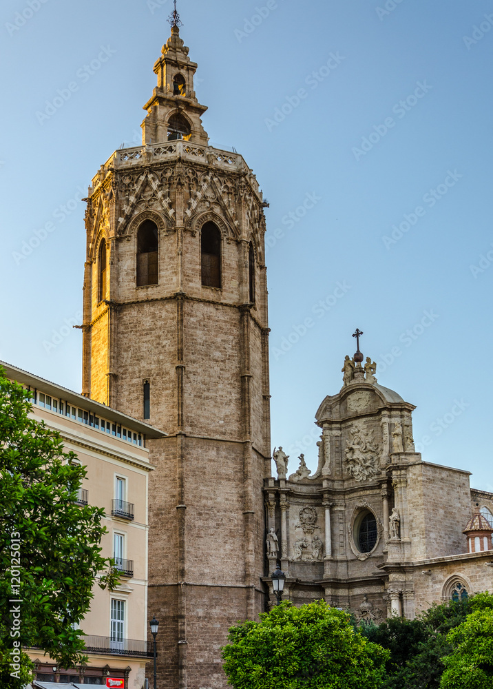 Solemn bell tower in sunlight and part of Cathedral facade in Valencia, Spain