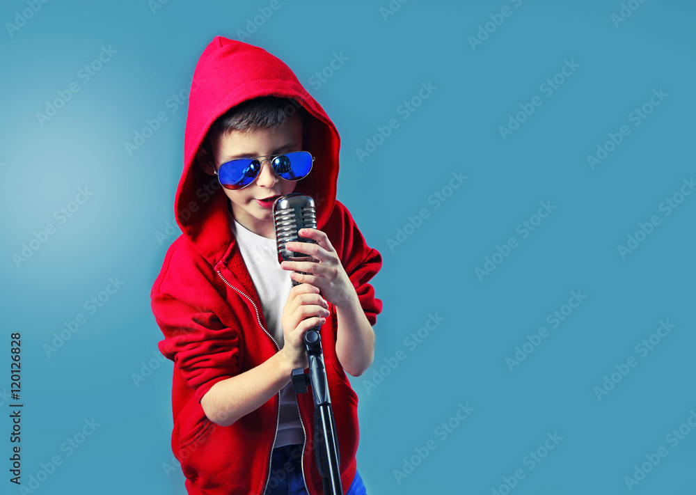 Little boy singing with microphone on blue background. Little boy singing with microphone on blue background.