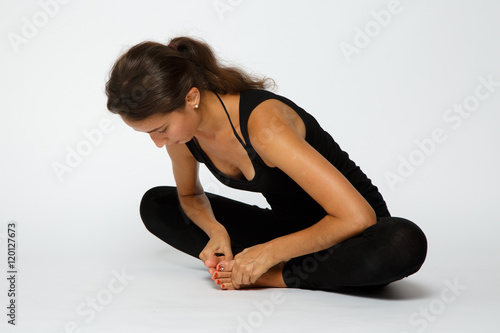 Girl makes yoga exercise on the white background in black