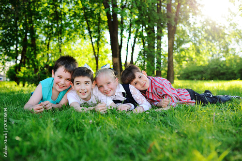 four children lie on their stomachs on the grass and smiling