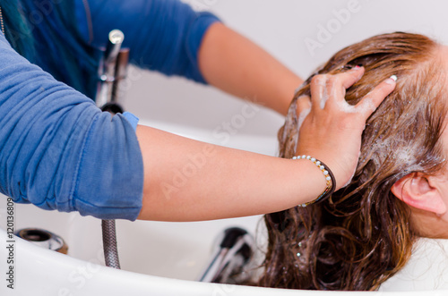 Massages inside a hairdressing saloon, hands washing with a nice shampoo a long hair