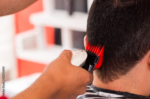 Close up of man hair cut with a machine, red and black tool