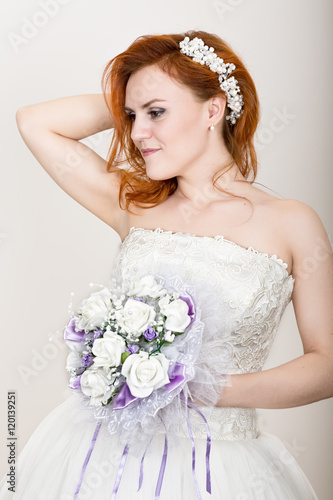 red-haired bride in a wedding dress holding wedding bouquet, bright unusual appearance. Beautiful wedding hairstyle and bright make-up