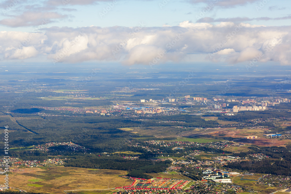 Small town near the forest in Russia. Aerial view of thick clouds and their shadows over the land, the landscape. 