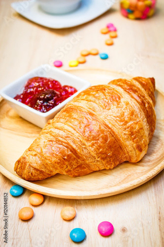 Tasty croissants with jam on wooden background.