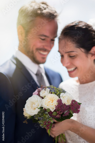  Portrait of smiling newlyweds, focus on the bride's bouquet