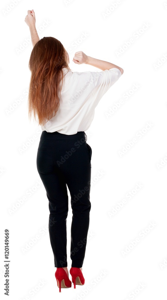 Back view of joyful woman celebrating victory hands up. Rear view people collection. backside view of person. Isolated over white background. slender redhead in a jeans shows symbol of success or Back view of joyful woman celebrating victory hands up. Rear view people collection. backside view of person. Isolated over white background. slender redhead in a jeans shows symbol of success or