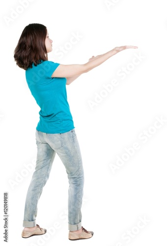 Back view of pointing woman. beautiful brunette girl in jeans. Rear view people collection. backside view of person. Isolated over white background.