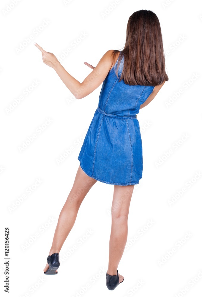 Back view of young brunette woman pointing at wall. cheerful girl in dress. Rear view people collection. backside view of person. Isolated over white background. Back view of young brunette woman pointing at wall. cheerful girl in dress. Rear view people collection. backside view of person. Isolated over white background.