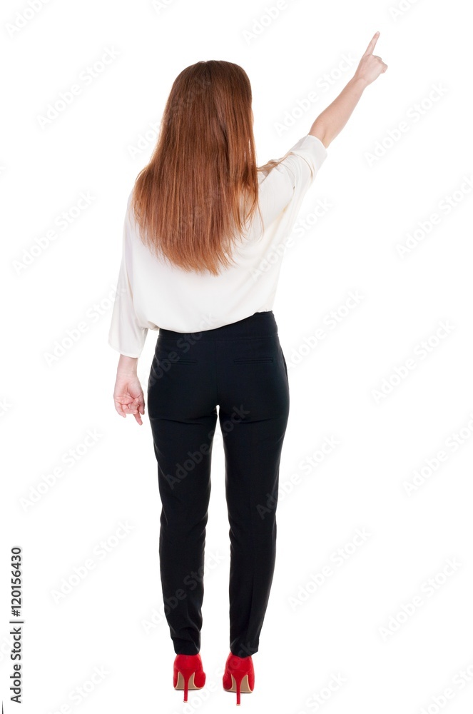 Back view of young redhead business woman pointing at wall. beautiful girl in dark suit. Rear view people collection. backside view of person. Isolated over white background. Back view of young redhead business woman pointing at wall. beautiful girl in dark suit. Rear view people collection. backside view of person. Isolated over white background.