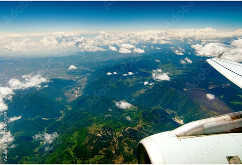Mountains under the wing of the aircraft. mountain peaks covered with green meadows in the clouds