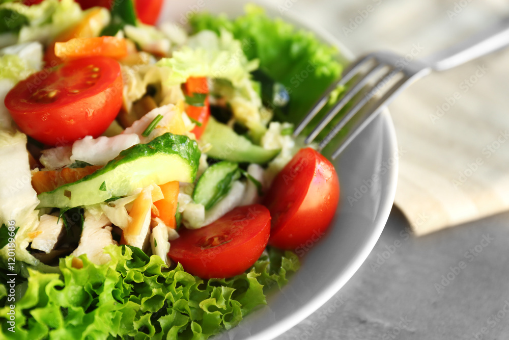 Plate with fresh salad on gray table