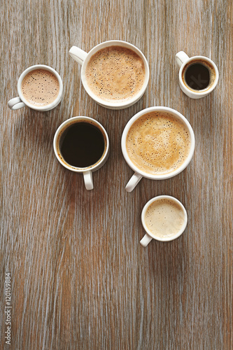 Cups of coffee on wooden background, top view