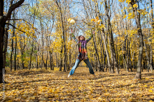 Joyful woman jumping for joy, tossing up leaves