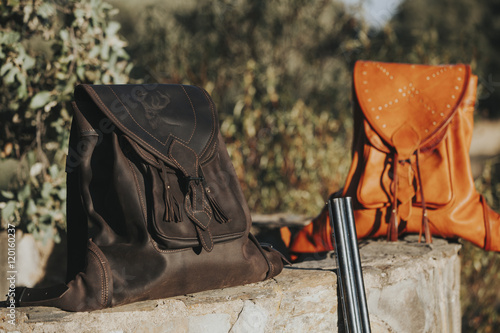 Two leather bags in a stone wall at the countryside. Hunting concept.